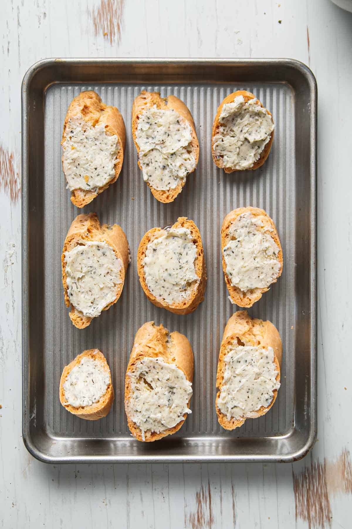 Gluten-free garlic bread arranged in rows on a small baking sheet. 