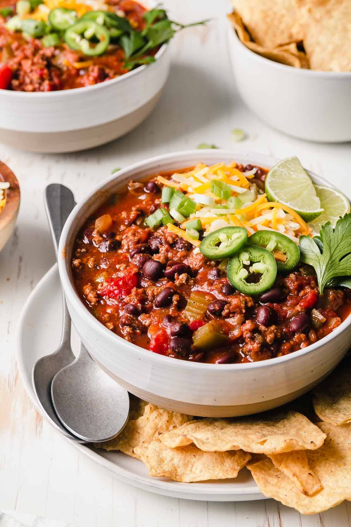 Gluten-free chili in a large bowl topped with cheese, jalapeño, and green onion.