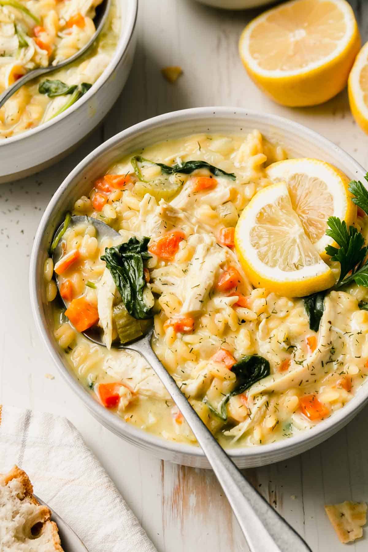 Lemon chicken orzo soup in a bowl garnished with lemon slices and parsley.