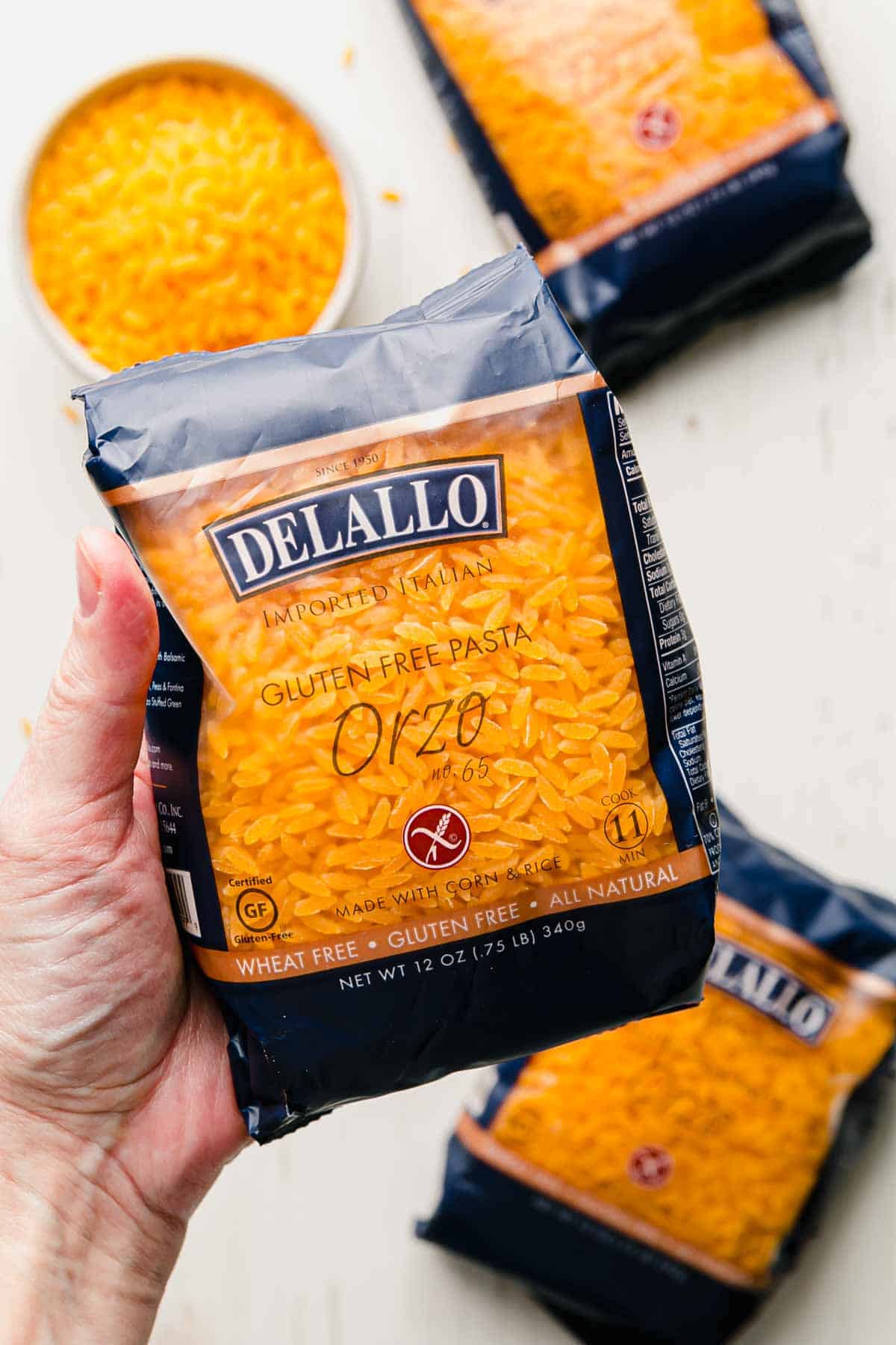 A package of dellalo gluten free orzo held by a hand.