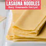 Homemade gluten free lasagna noodles stacked and folded over on a white enameled pan.