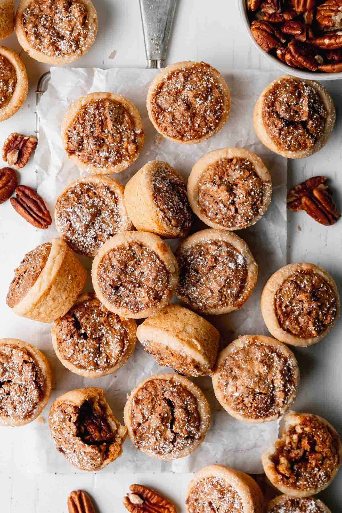 A pile of pecan tassies on a wire rack with parchment paper.