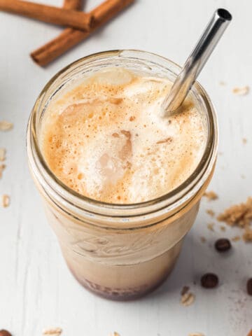 Brown sugar shaken espresso with foamy top and ice in mason jar with metal straw.