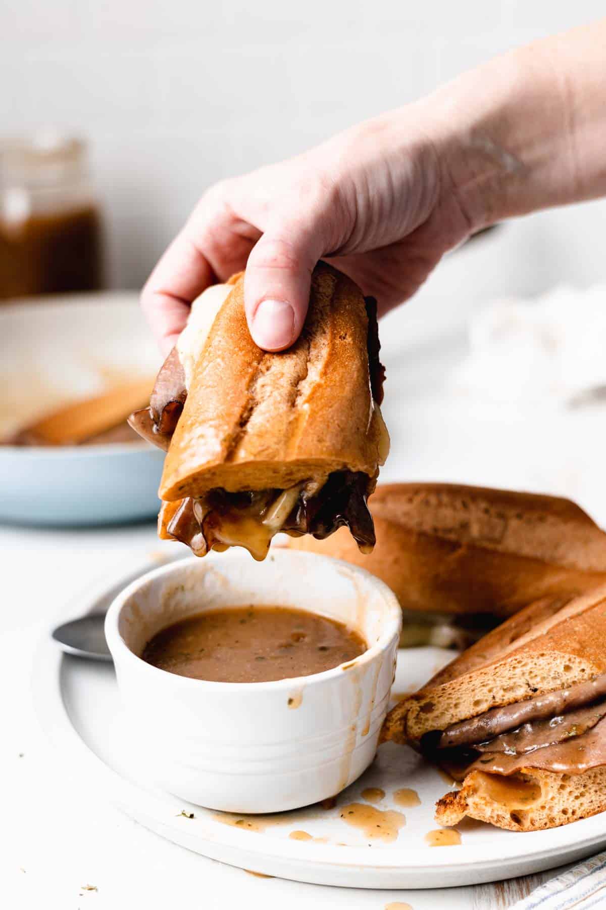 French dip sandwich dipped in a cup of gluten-free au jus.