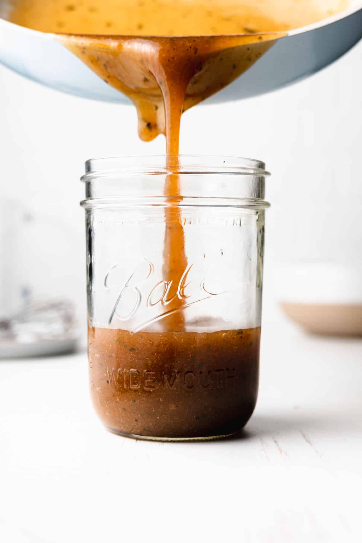 Gluten free au jus poured into mason jar from blue pan.