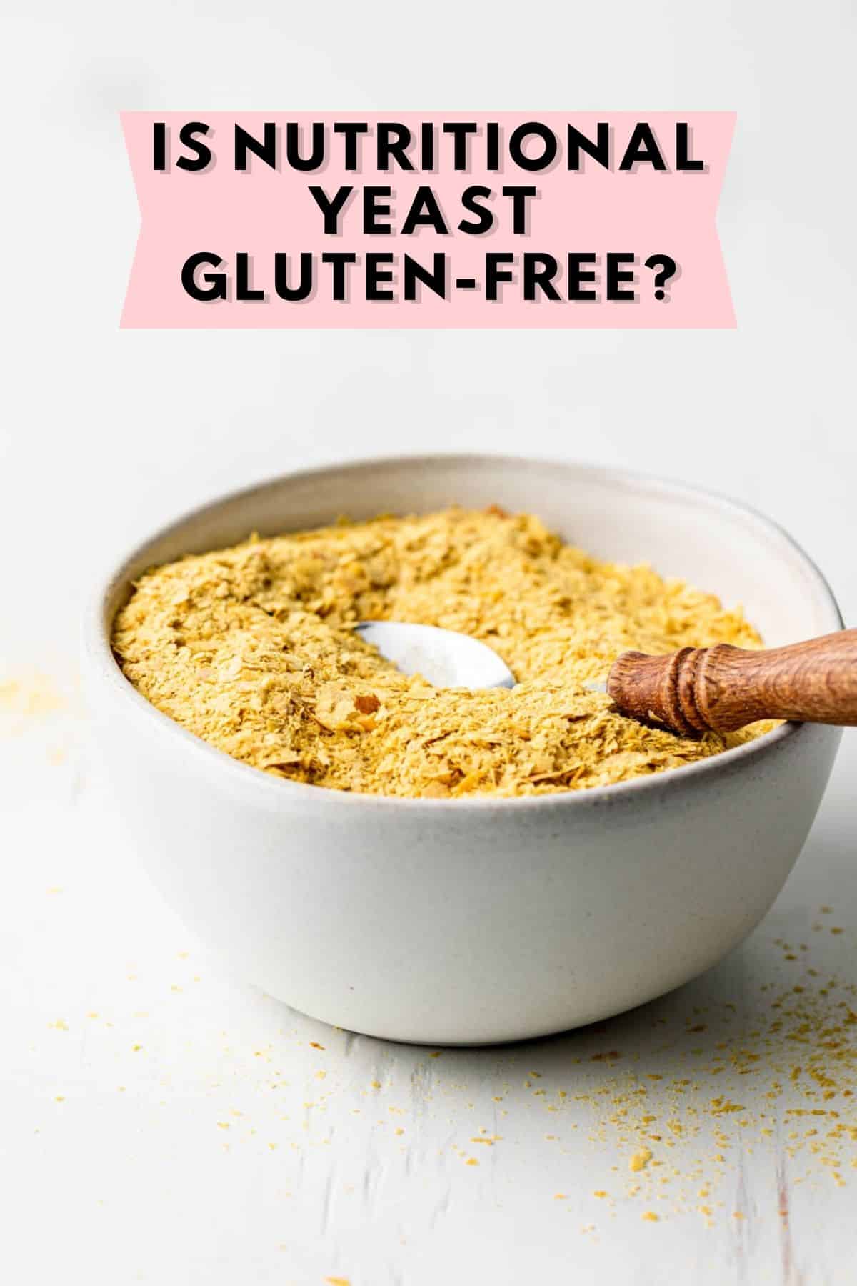 Nutritional yeast flakes in a small bowl with a spoon that has a wooden handle. 