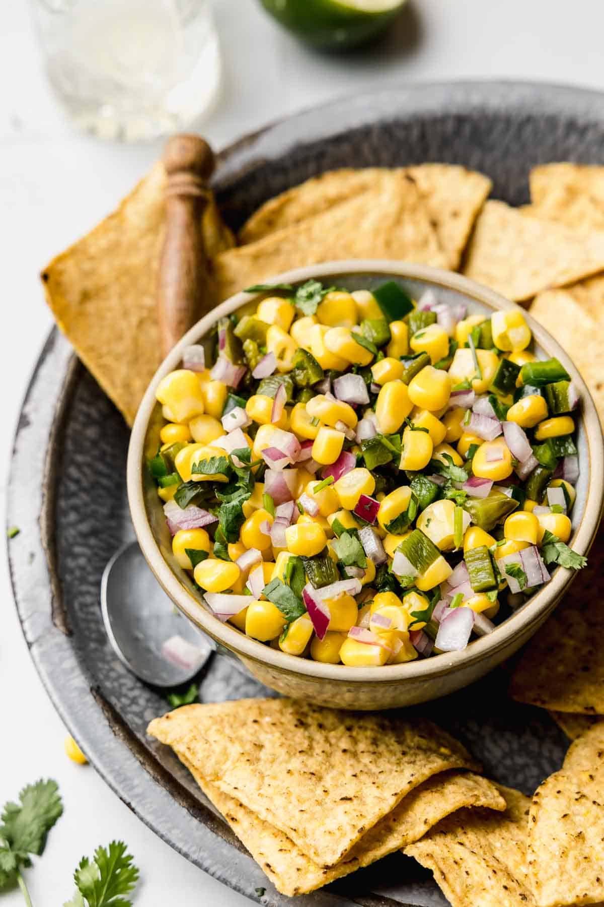 Sweet corn salsa in a small bowl next to tortilla chips.