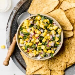 Chipotle roasted chili corn salsa in small bowl next to chips and spoon.