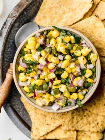 Chipotle roasted chili corn salsa in small bowl next to chips and spoon.