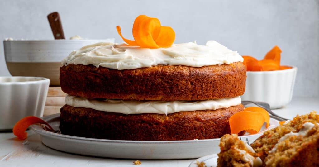 Gluten free carrot cake with pineapple on large plate with carrot curls as garnish.