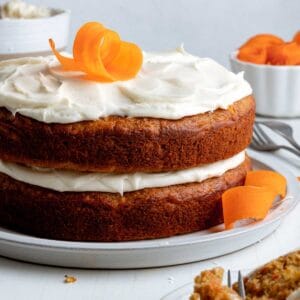 Gluten free carrot cake with pineapple on large plate with carrot curls as garnish.