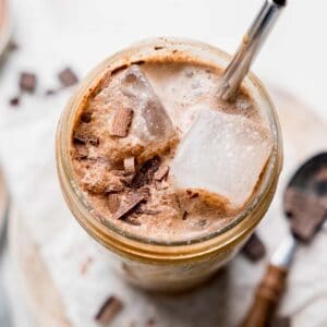 Chocolate shaken espresso in a large mason jar with ice and chocolate shavings.