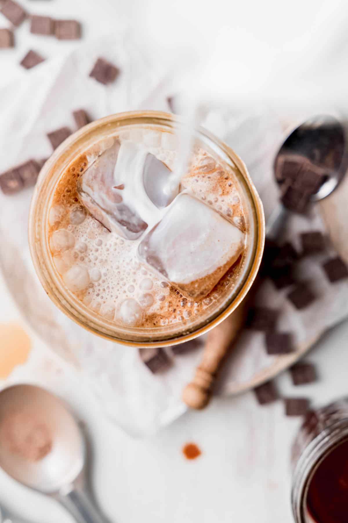 Milk pouring into the glass with the espresso over the ice.