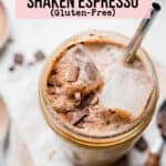 Chocolate shaken espresso in a large mason jar with ice and chocolate shavings.