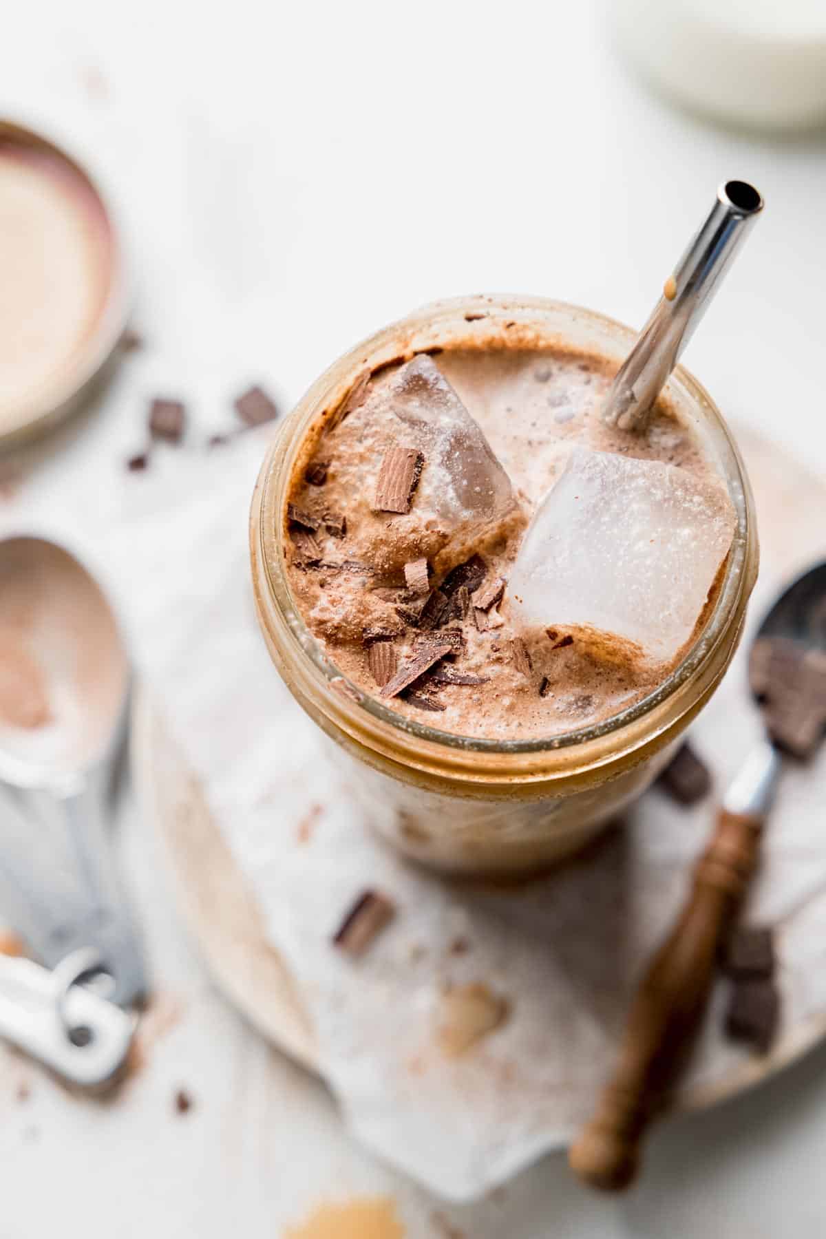 Chocolate shaken espresso in a large mason jar with ice and chocolate shavings.