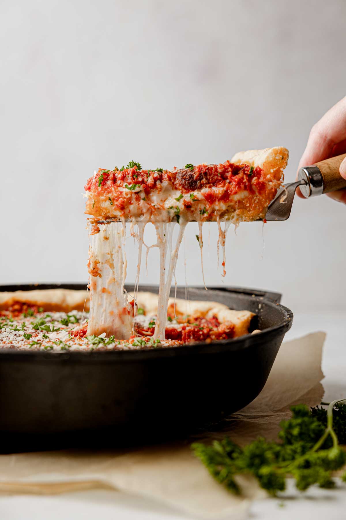 Slice of pizza lifted from pan with cheese pull.