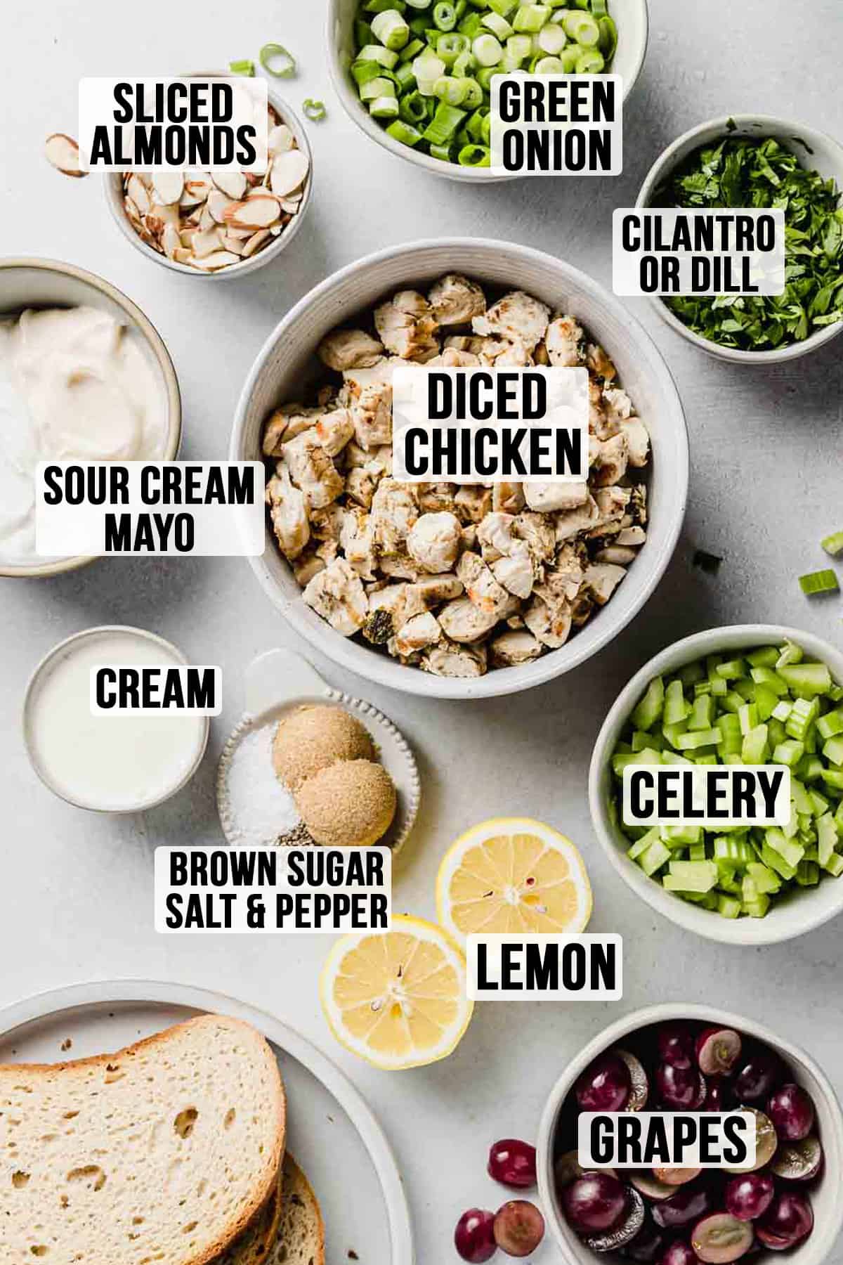 Ingredients for chicken salad measured out in bowls on white surface.