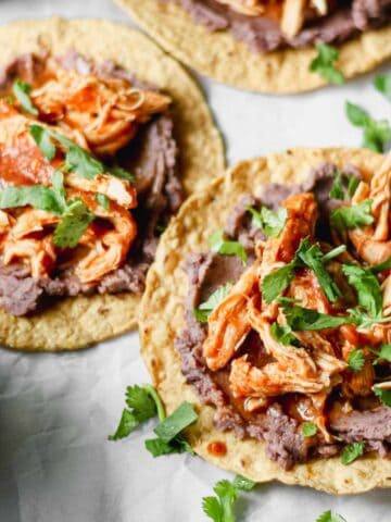 Shredded chicken Tinga on top of tostadas with refried black beans and cilantro.