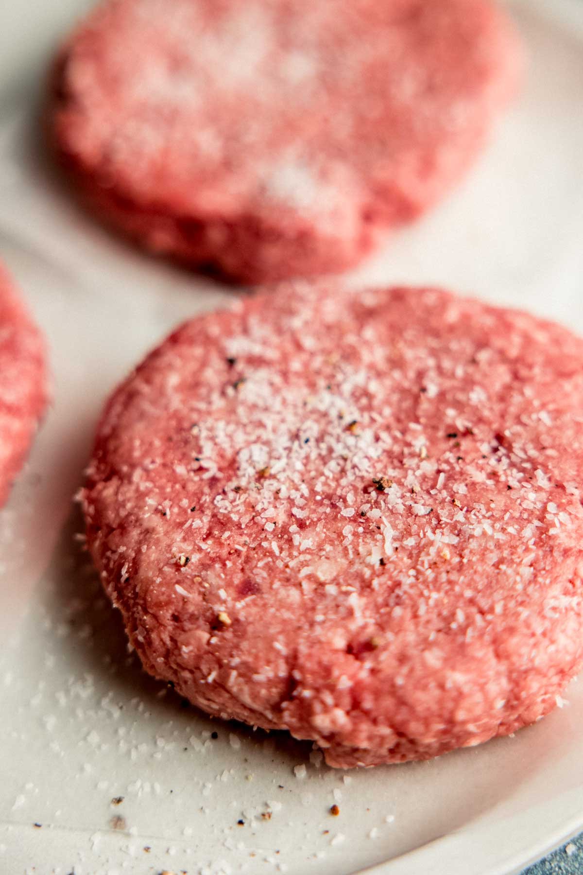 Ground beef burger patties liberally seasoned with salt and pepper.