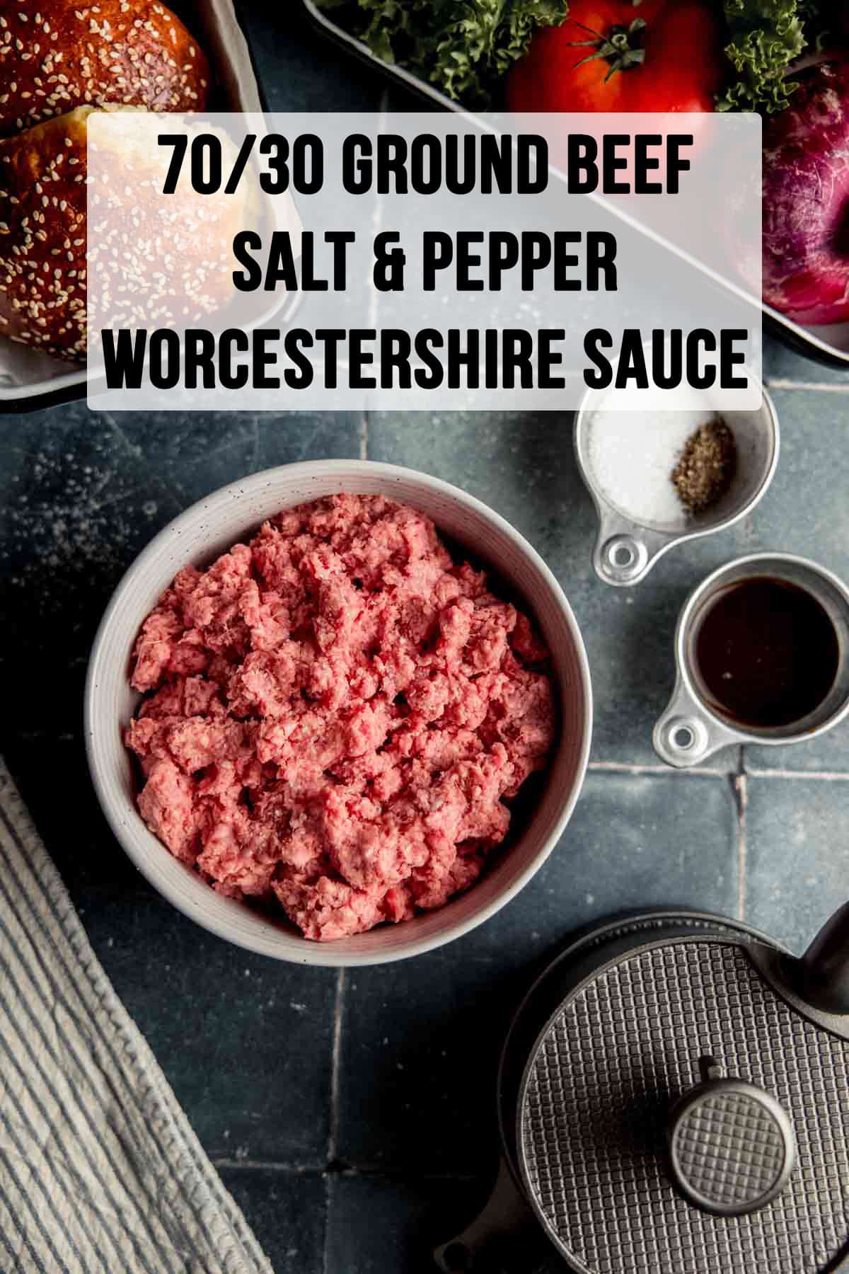 Ground beef in a bowl next to Worcestershire sauce, salt, pepper, and a burger press.