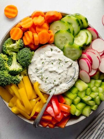 Colorful veggie tray with bowl of gluten-free ranch in center.