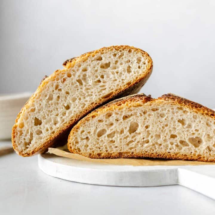 A loaf of gluten-free sourdough cut in half, one half leaning on the other.