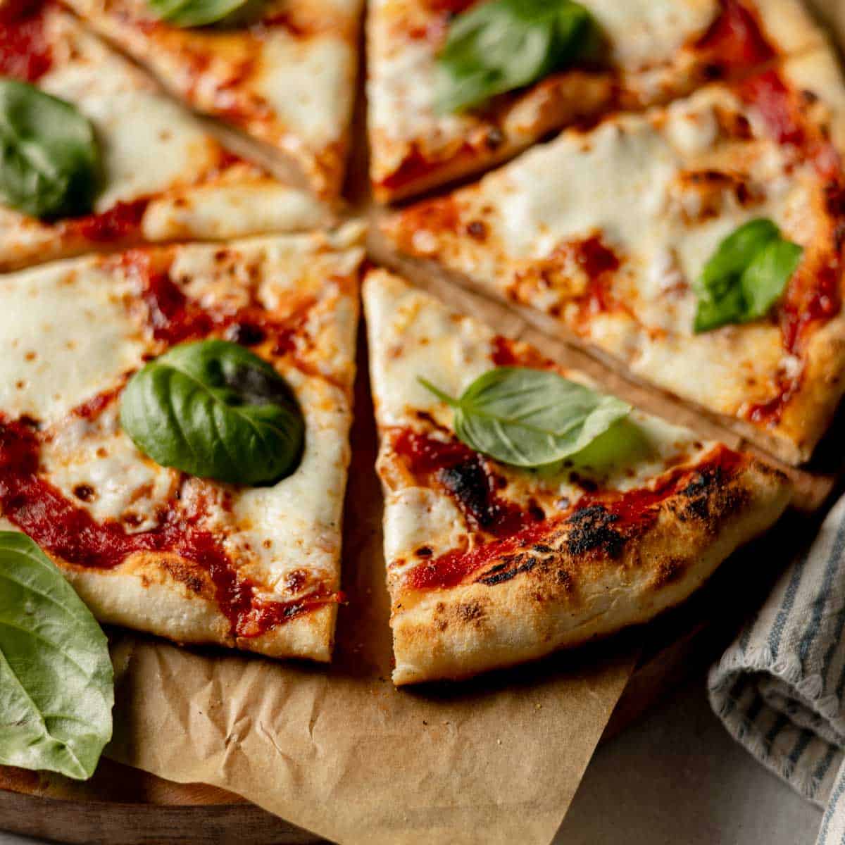 Gluten-free pizza cooked in an Ooni pizza oven with perfectly charred crust, garnished with basil.