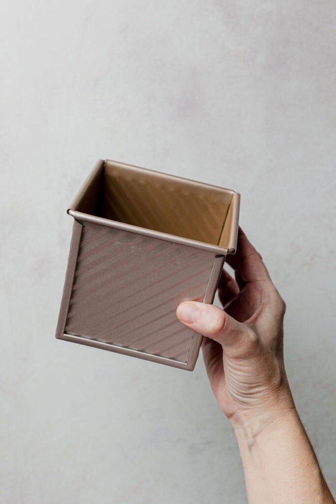 Hand holding a small pullman loaf pan.