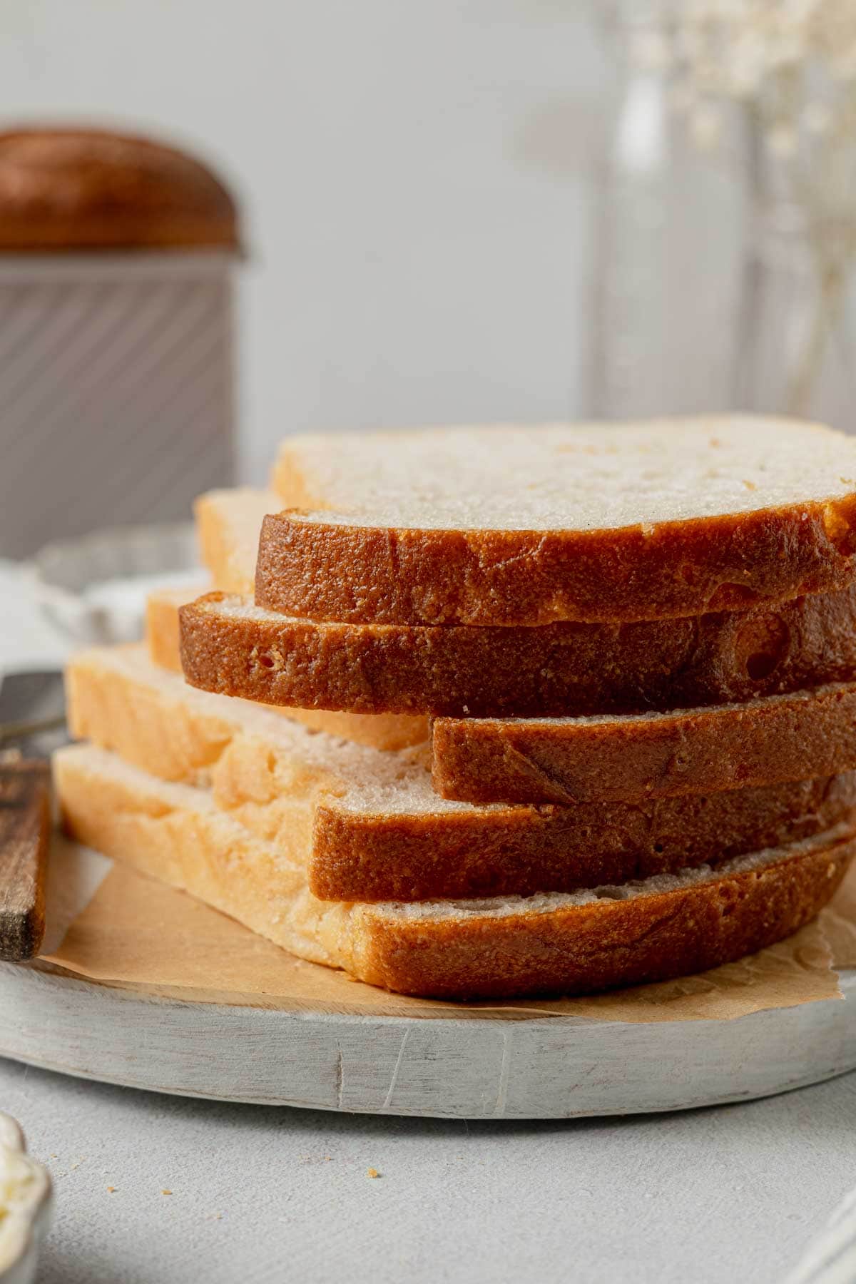 Slices of gluten-free sandwich loaf stacked on a wooden board.