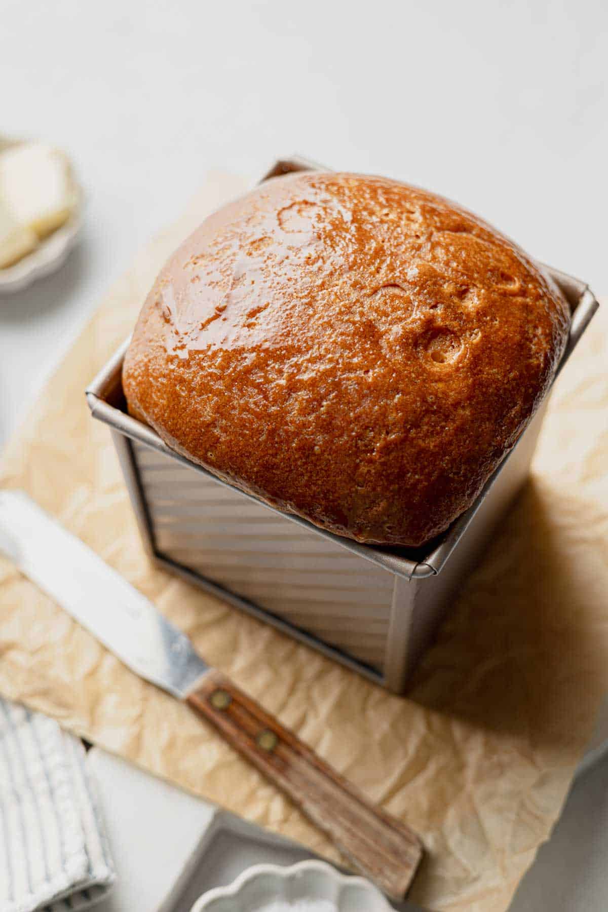 Baked gluten-free sourdough sandwich loaf in pullman pan with golden brown top crust.