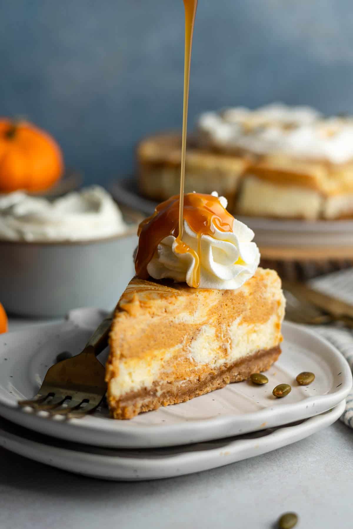 Caramel drizzling down onto a slice of gluten-free cheesecake swirled with pumpkin.