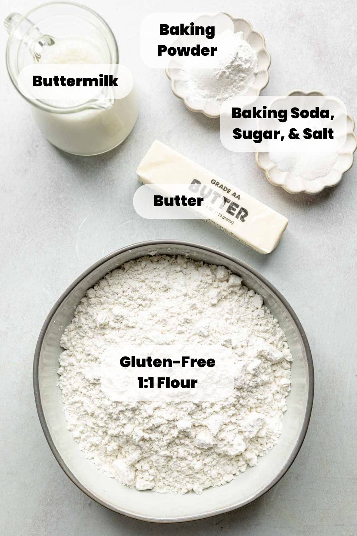 Gluten free flour and other ingredients measured out in bowls next to a stick of butter.