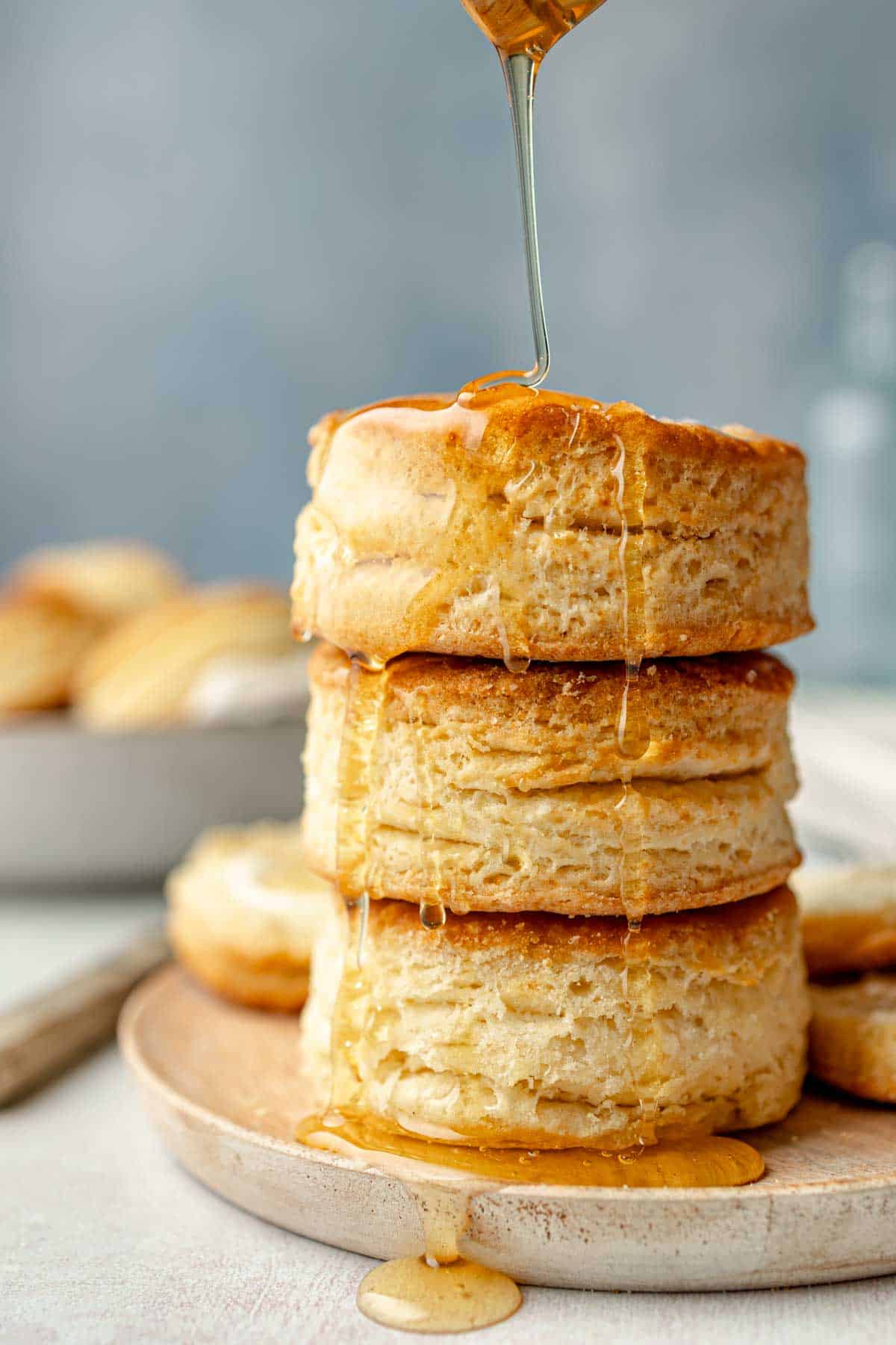 A stack of gluten-free biscuits with honey dripping down from the top.
