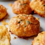 Gluten-free cheddar bay biscuit with melted butter and parsley on top.