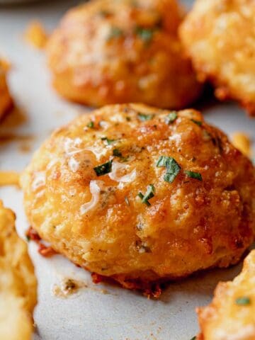 Gluten-free cheddar bay biscuit with melted butter and parsley on top.