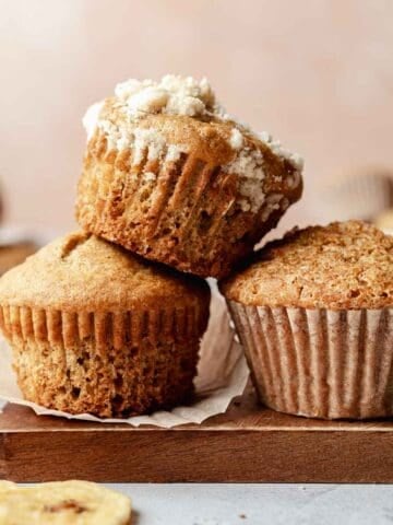 Gluten free sourdough discard banana muffins stacked on top and next to each other. One has streusel topping.