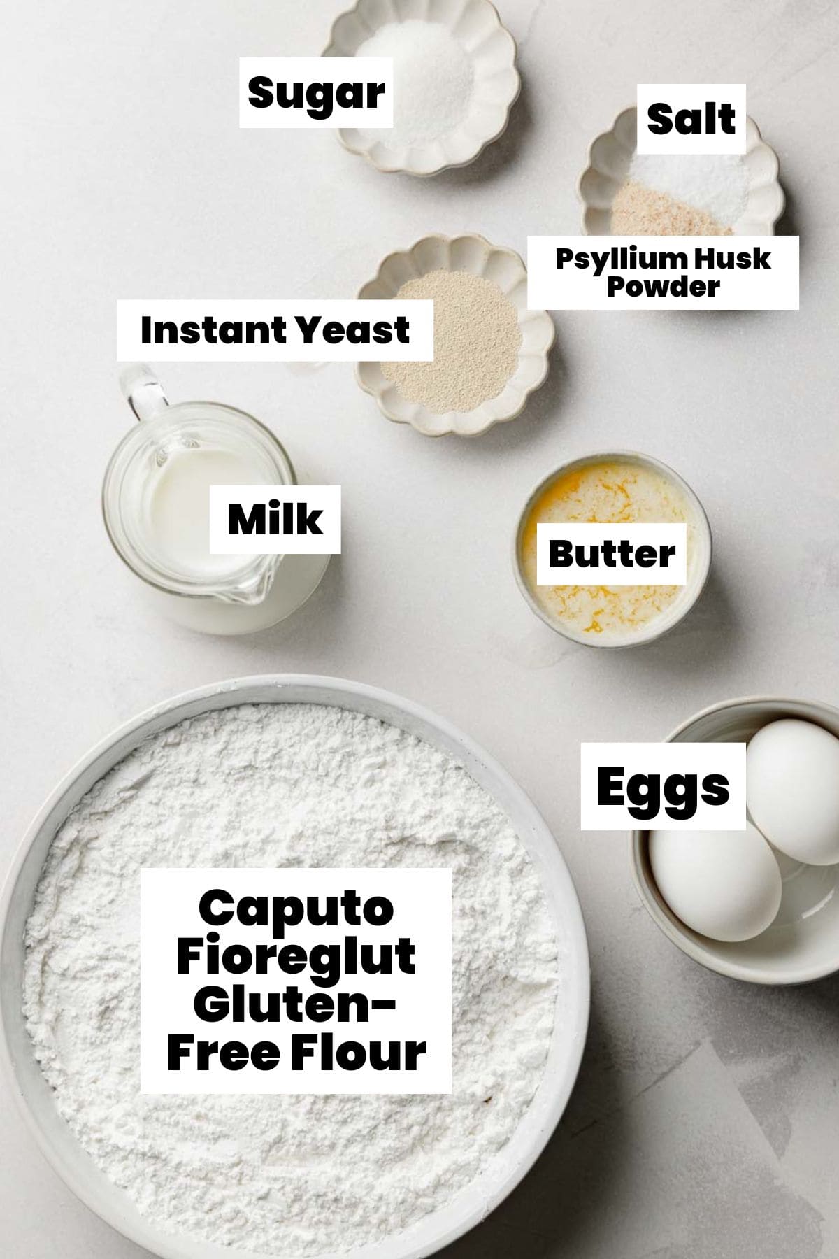 Flat lay of ingredients for gluten-free dinner rolls, including Caputo Fioreglut gluten-free flour, sugar, salt, psyllium husk powder, instant yeast, milk, melted butter, and eggs.
