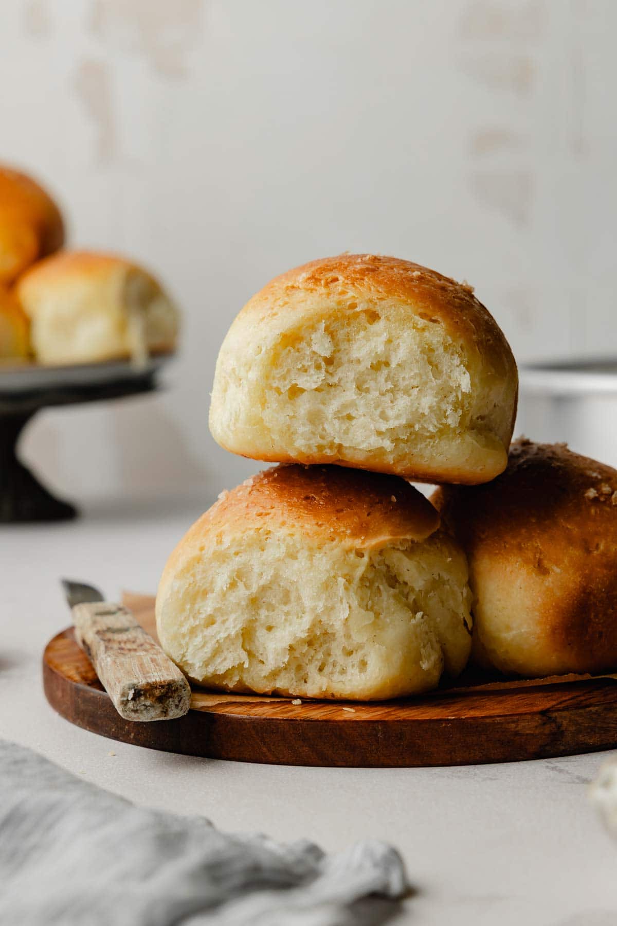 Stack of baked gluten-free dinner rolls on a wooden board, showing the soft, fluffy interior.
