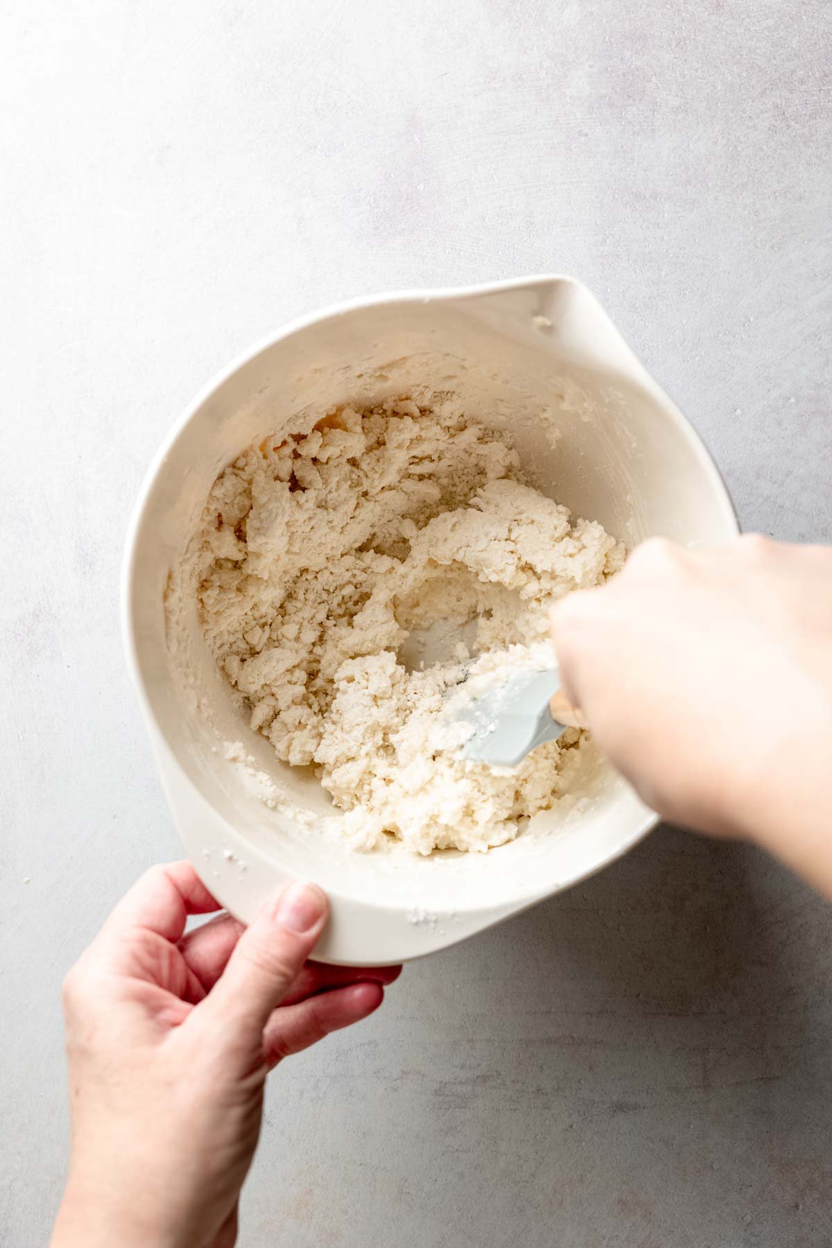 Mixing biscuit dough with a spatula in a bowl.