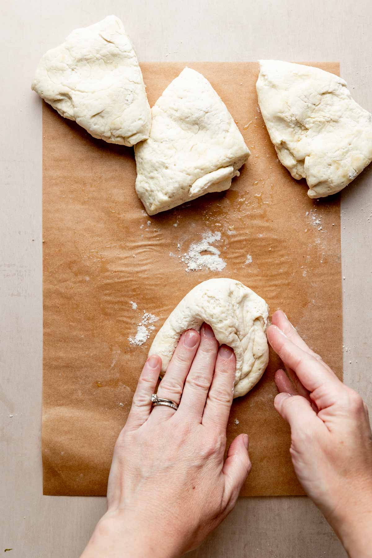 Dough cut into four portions, one is kneaded with hands into ball.