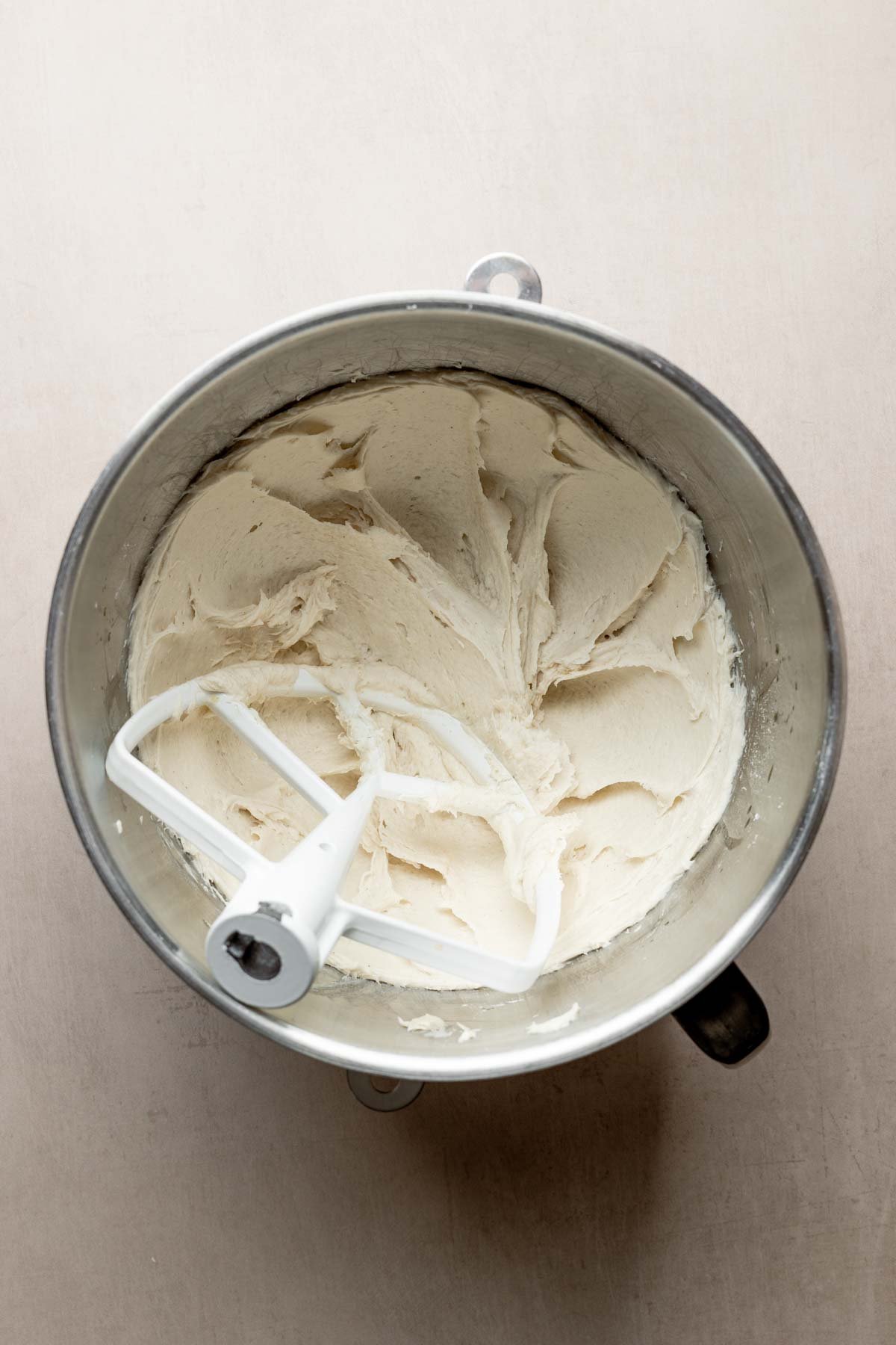 Mixed pita bread dough in stand mixer bowl showing thick batter texture. 