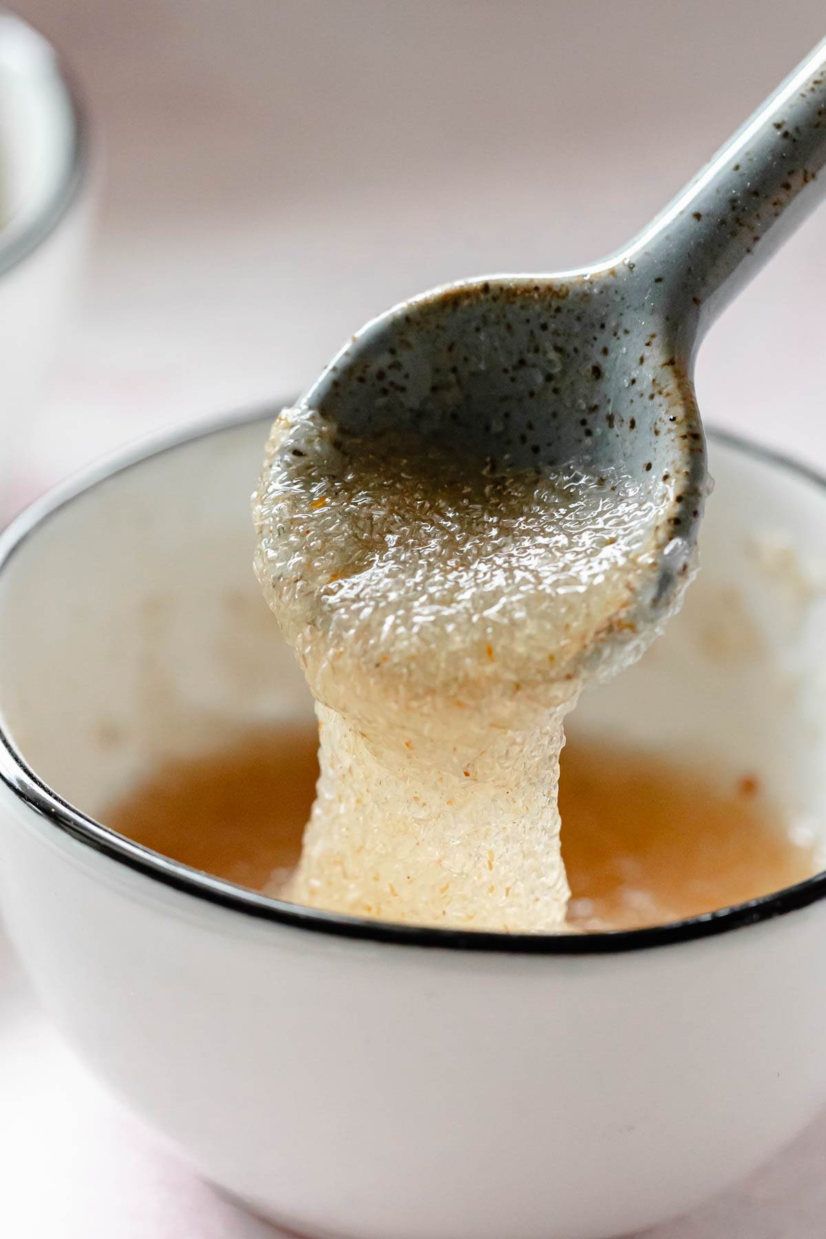 Psyllium whole husk gel in small bowl lifted by spoon.
