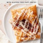 Close-up of a single pumpkin danish on a white speckled plate. The flaky crust and pumpkin filling are topped with a neat drizzle of icing.