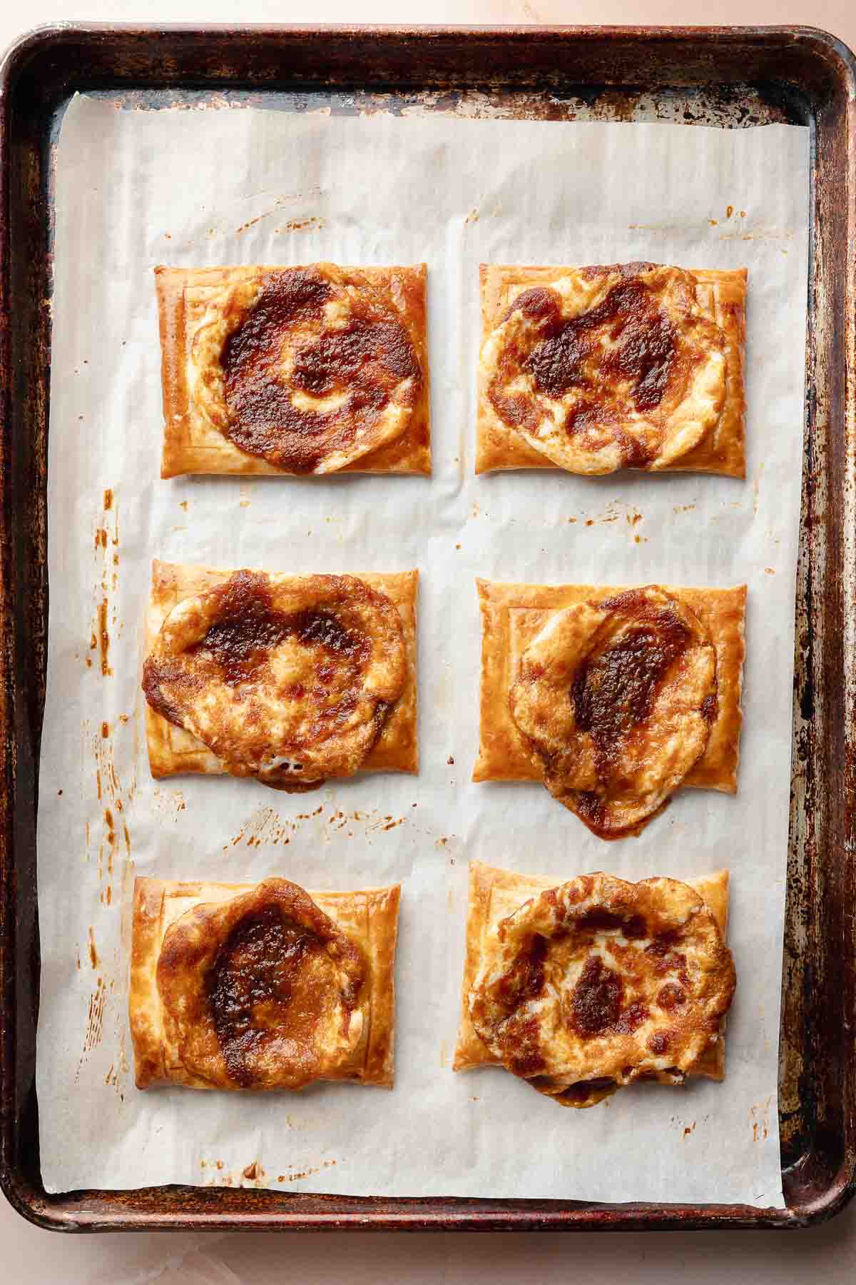 Baked pumpkin danishes on the tray. The pastries are golden and puffed with caramelized, spiced filling in the center.
