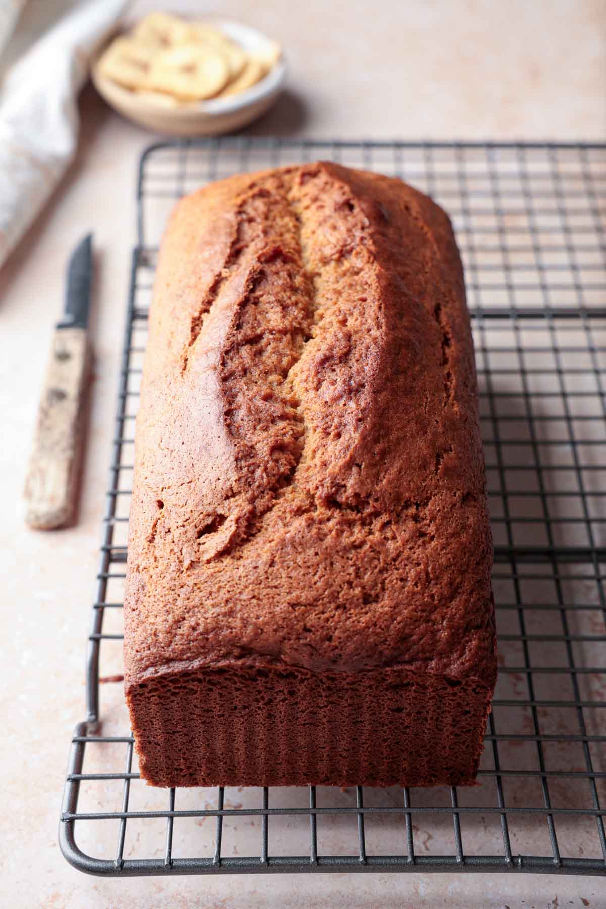 Whole loaf of gluten-free banana bread cooling on wire rack.