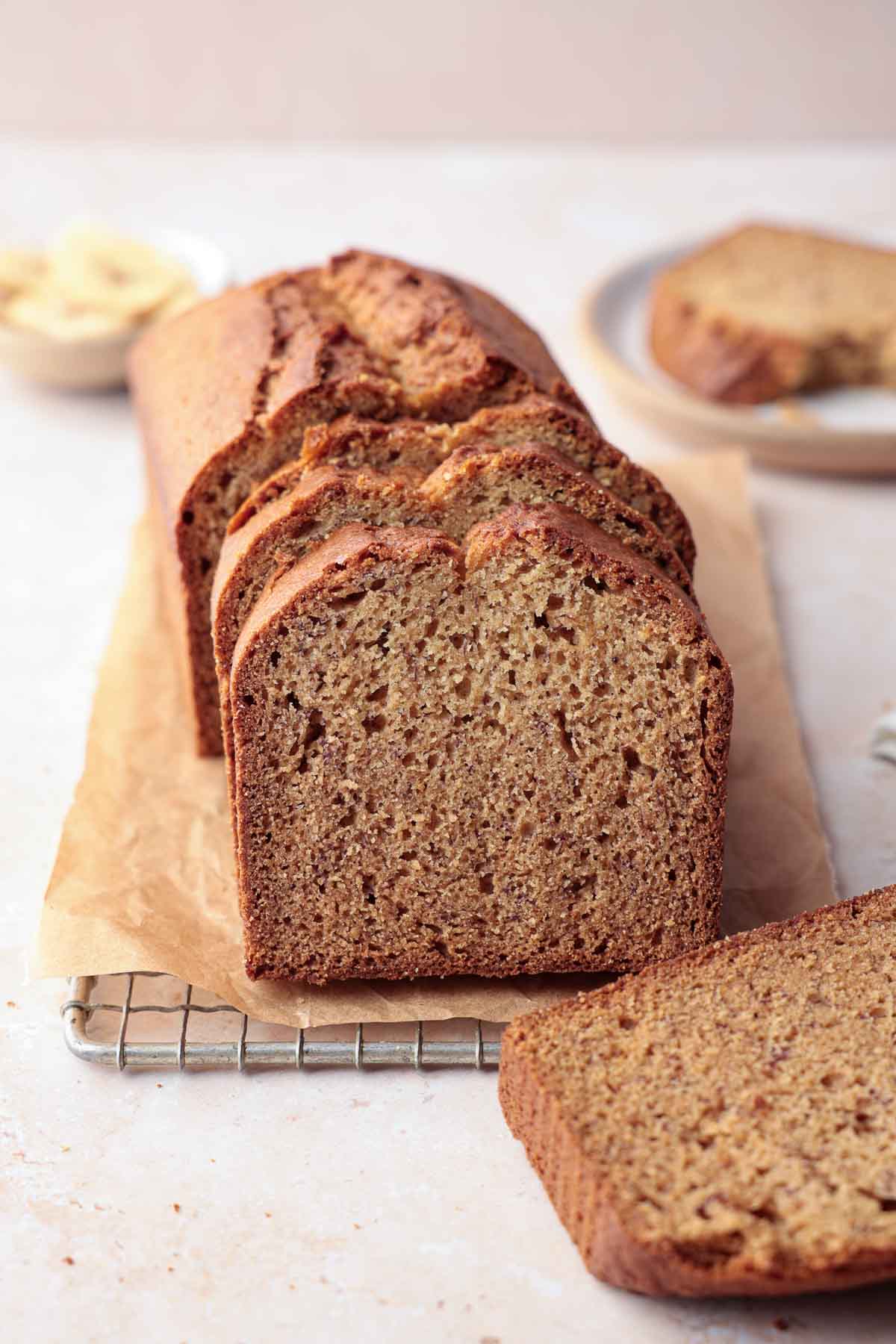 Sliced gluten-free banana bread loaf on parchment and cooling rack.