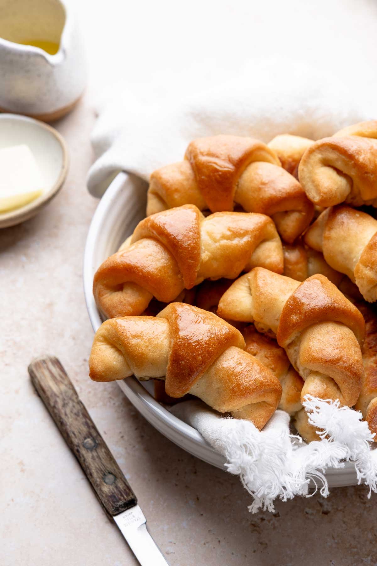 Bowl lined with cloth, filled with baked gluten-free crescent rolls.