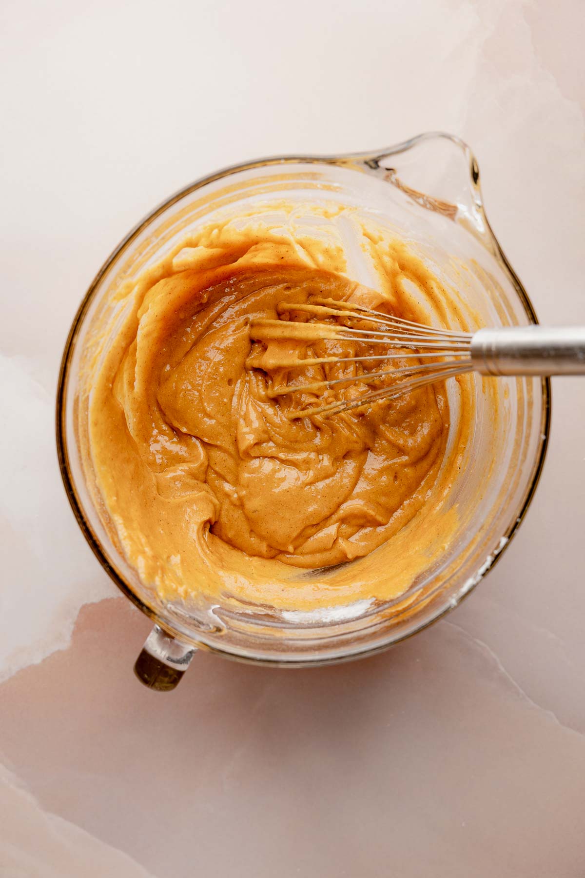 Thicker pumpkin bread batter in mixing bowl with whisk.