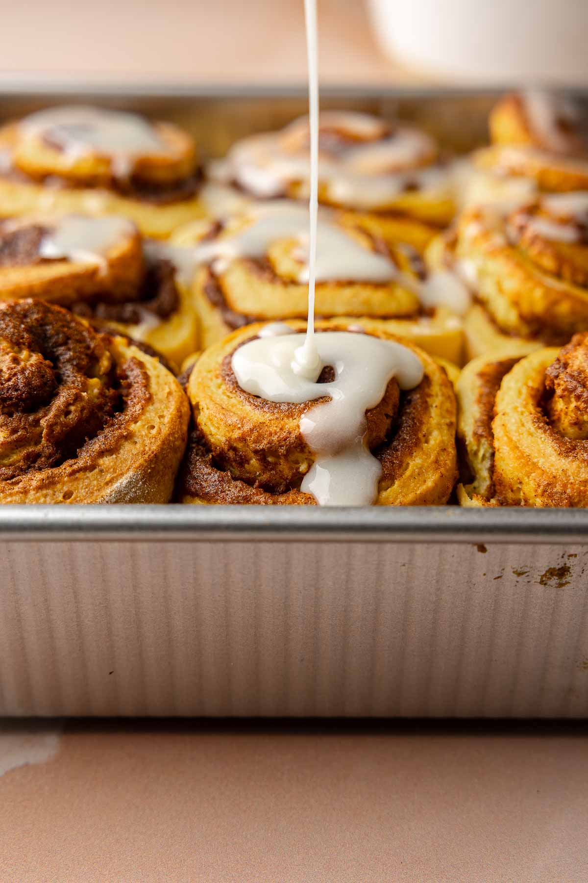 Icing drizzle over baked rolls.