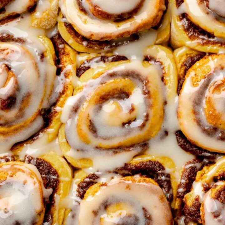 Close-up of gluten free pumpkin cinnamon rolls with icing covering swirls.